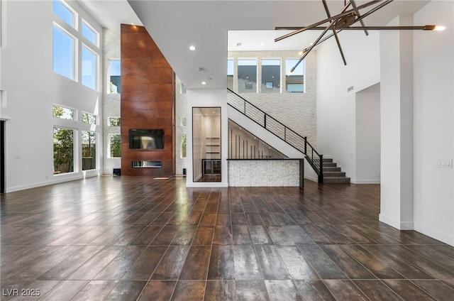 unfurnished living room featuring a notable chandelier, a towering ceiling, and a healthy amount of sunlight