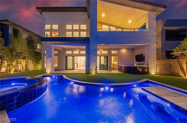 pool at dusk with a yard and an in ground hot tub