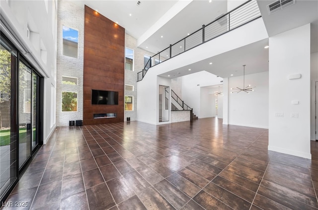 unfurnished living room with a fireplace, a high ceiling, and a chandelier