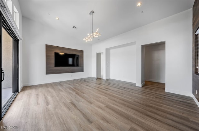 unfurnished living room featuring a chandelier and wood-type flooring