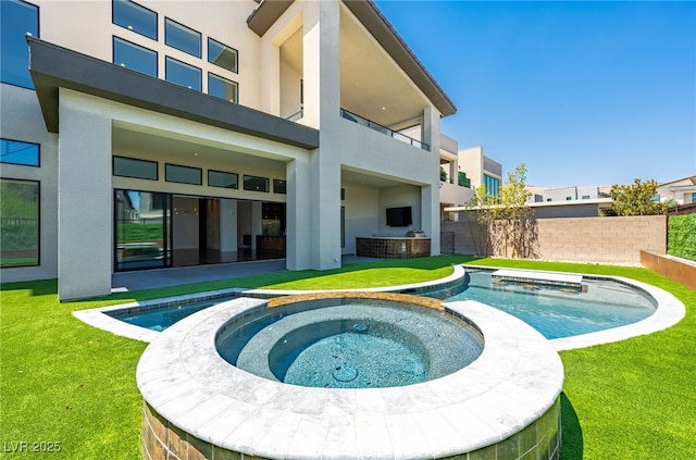 rear view of house featuring a pool with hot tub and a lawn