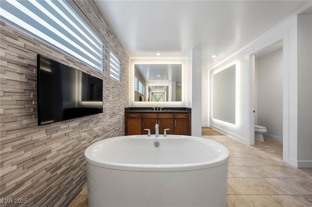 bathroom featuring a washtub, tile patterned floors, vanity, and toilet