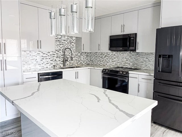 kitchen with hanging light fixtures, light stone countertops, black appliances, and white cabinets