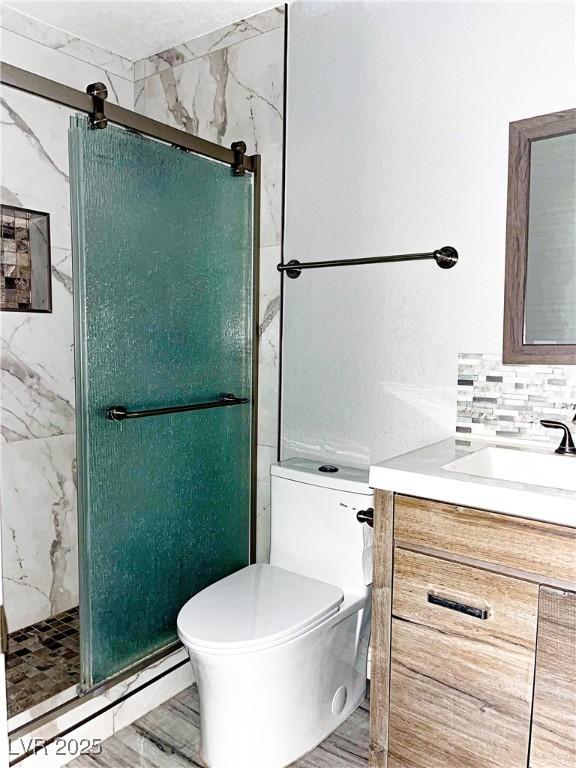 bathroom featuring toilet, vanity, an enclosed shower, and tasteful backsplash