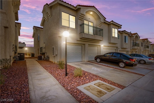 view of front facade featuring a garage, driveway, a tiled roof, and stucco siding