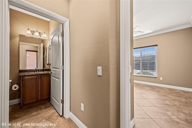 hallway with sink, crown molding, and light tile patterned floors