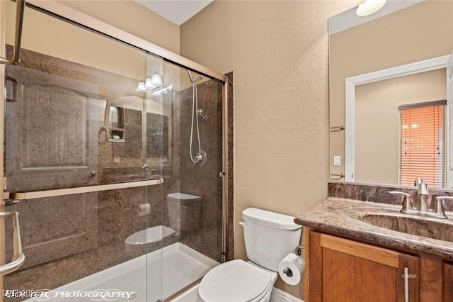 bathroom with vanity, a shower with door, and toilet