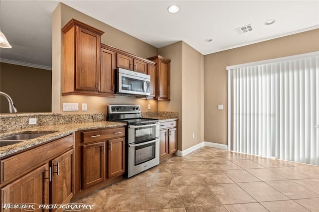 kitchen featuring appliances with stainless steel finishes, light tile patterned floors, sink, and light stone countertops