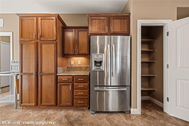 kitchen featuring light stone counters and stainless steel fridge