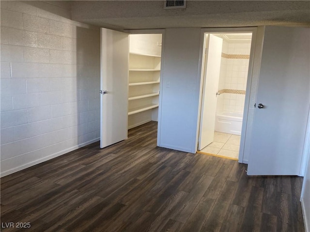 unfurnished bedroom with dark hardwood / wood-style flooring, a closet, and a spacious closet