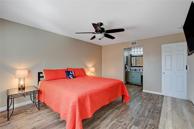 bedroom with ceiling fan, ensuite bath, and wood-type flooring