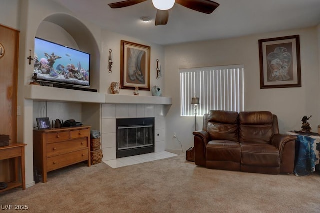 carpeted living room with a tile fireplace and ceiling fan