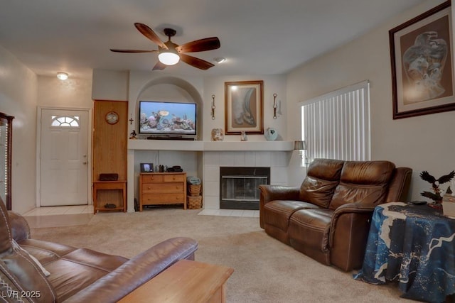 carpeted living room featuring ceiling fan and a tiled fireplace