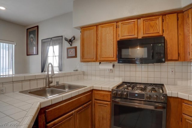 kitchen with tile counters, kitchen peninsula, sink, tasteful backsplash, and stainless steel gas stove