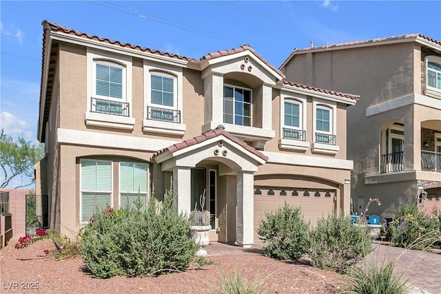 mediterranean / spanish house with a garage, a tiled roof, and stucco siding