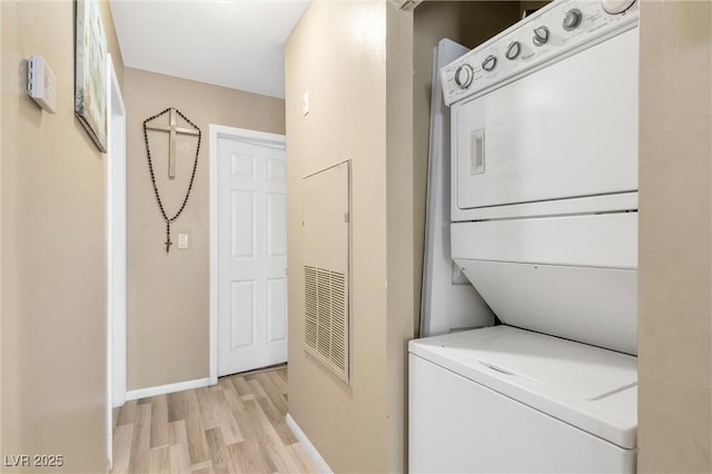 washroom featuring stacked washer and dryer and light hardwood / wood-style flooring