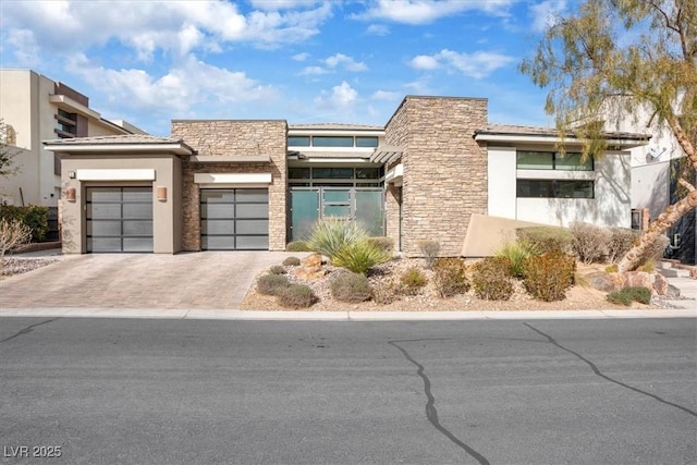 view of front of home with a garage, stone siding, driveway, and stucco siding