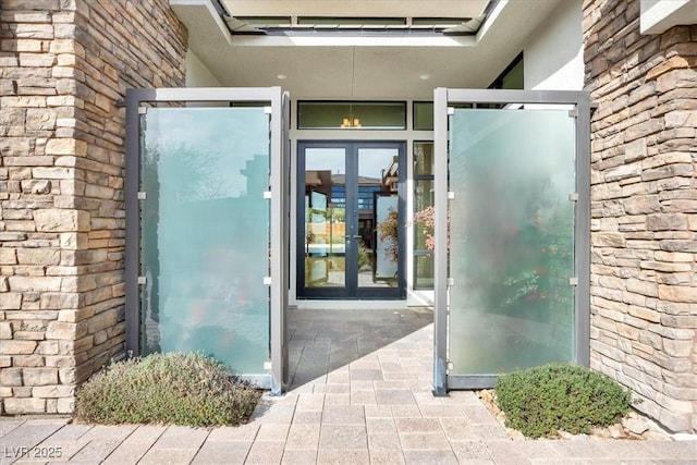 view of exterior entry featuring brick siding, stone siding, and french doors