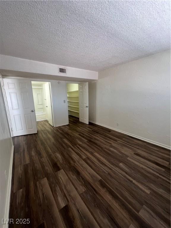 unfurnished bedroom with a textured ceiling, a closet, and dark hardwood / wood-style floors