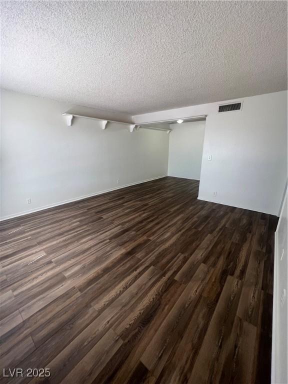 empty room with dark hardwood / wood-style flooring and a textured ceiling