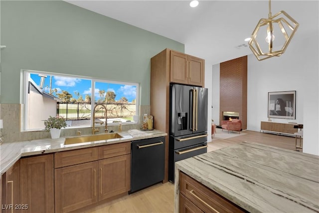 kitchen with light stone counters, decorative light fixtures, high quality fridge, a fireplace, and black dishwasher