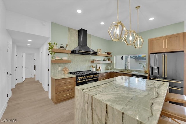 kitchen featuring sink, light stone counters, a kitchen breakfast bar, wall chimney exhaust hood, and black appliances