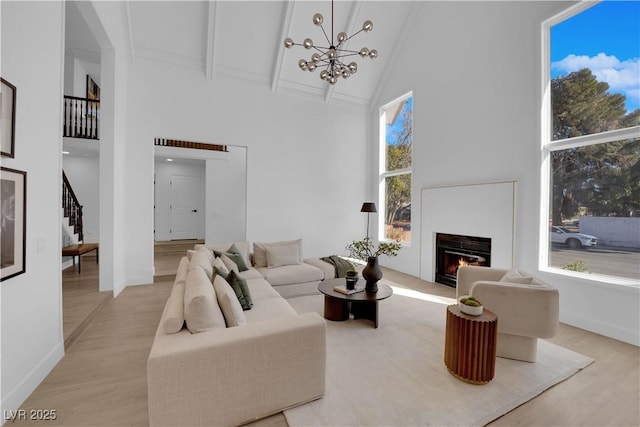 living room featuring an inviting chandelier, high vaulted ceiling, light hardwood / wood-style flooring, and beam ceiling