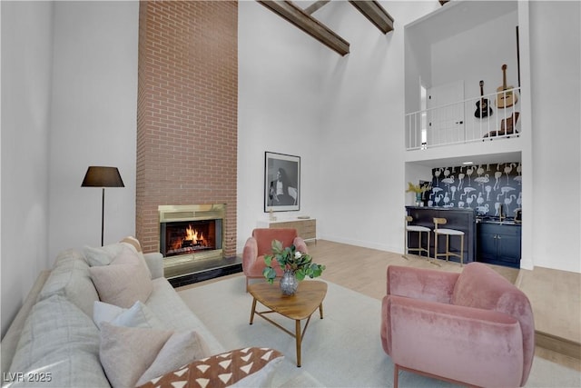 living room featuring a fireplace, light wood-type flooring, indoor bar, and a towering ceiling