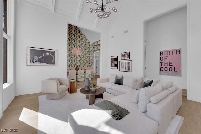 living room with a notable chandelier, high vaulted ceiling, beamed ceiling, and light hardwood / wood-style flooring