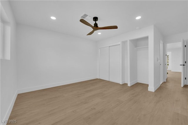 unfurnished bedroom with ceiling fan, light wood-type flooring, and multiple closets