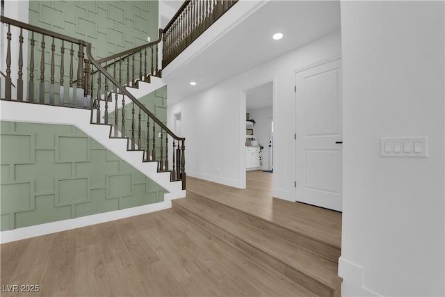 entryway with hardwood / wood-style floors and a towering ceiling