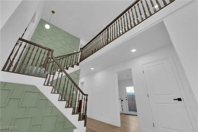 stairway with a towering ceiling and wood-type flooring