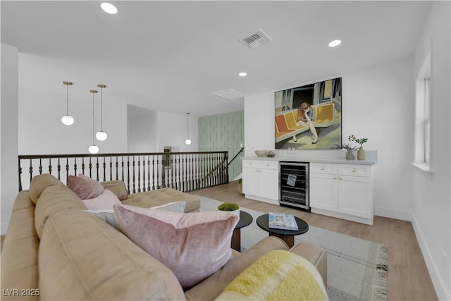 living room featuring bar area, light hardwood / wood-style floors, and beverage cooler