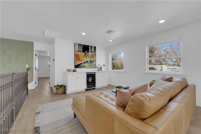 living room featuring wine cooler, light wood-type flooring, and bar