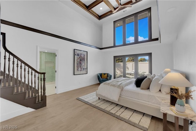 bedroom with coffered ceiling, wood-type flooring, beamed ceiling, connected bathroom, and a high ceiling