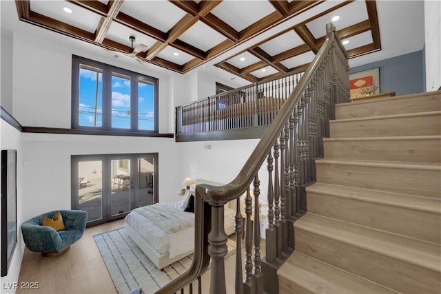 staircase with hardwood / wood-style floors, coffered ceiling, beamed ceiling, a towering ceiling, and french doors