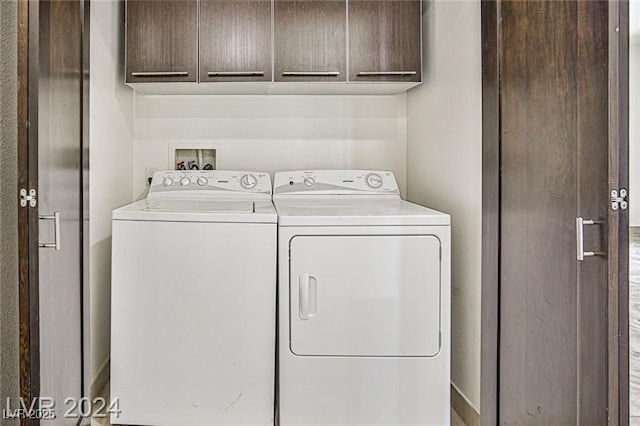 laundry room with washing machine and clothes dryer and cabinets