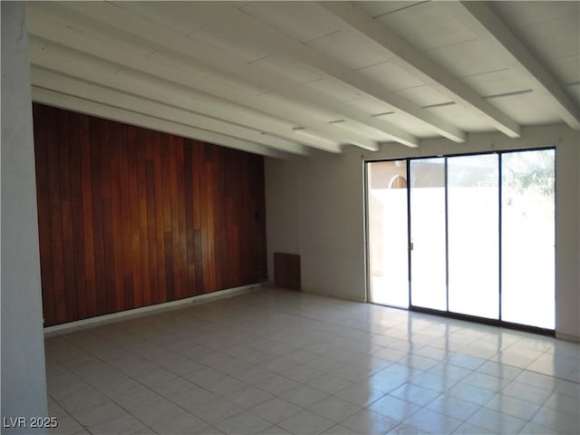 spare room featuring wooden walls and beam ceiling