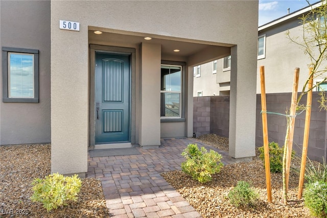 doorway to property with stucco siding and fence