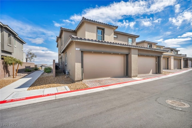 view of front of house with stucco siding, a garage, a tile roof, and fence