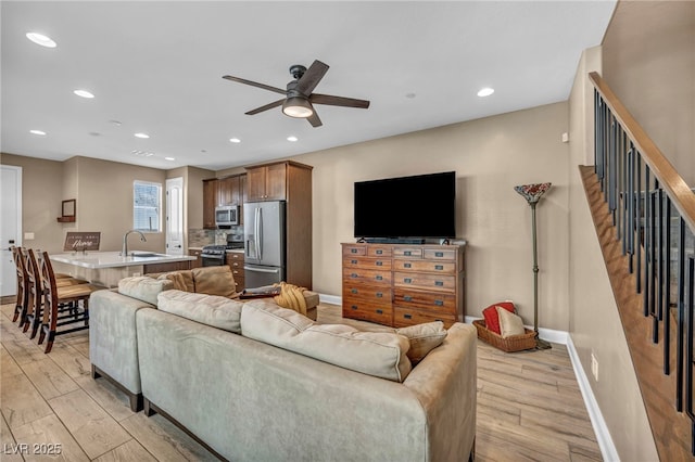 living area featuring a ceiling fan, recessed lighting, baseboards, and light wood finished floors