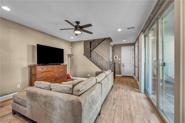 living area with stairway, visible vents, baseboards, and light wood-style floors