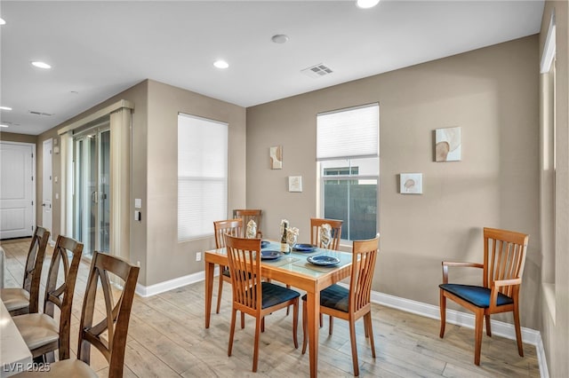 dining room with light wood-style floors, visible vents, and baseboards