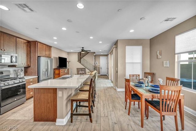 kitchen with an island with sink, visible vents, appliances with stainless steel finishes, and a sink