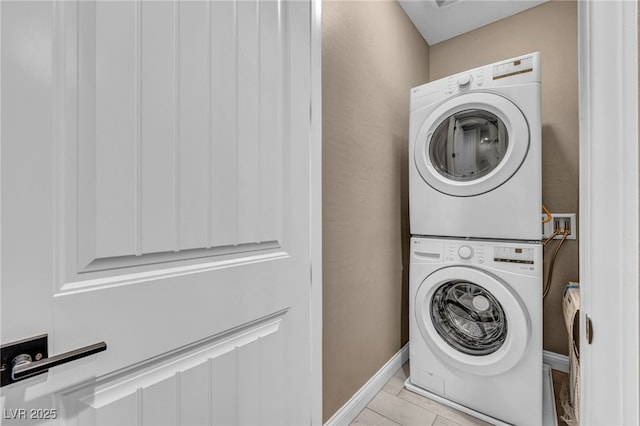 clothes washing area featuring baseboards and stacked washer and dryer