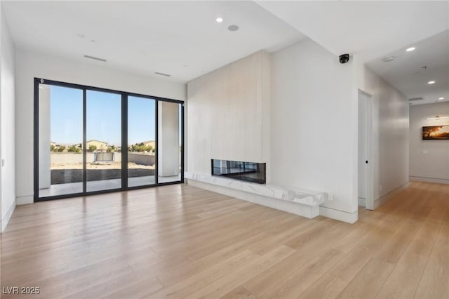 unfurnished living room featuring a high end fireplace and light hardwood / wood-style floors