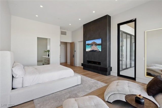 bedroom featuring light wood-type flooring, access to exterior, and a fireplace