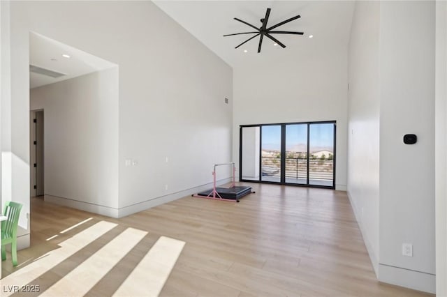 unfurnished room with light hardwood / wood-style floors and a towering ceiling