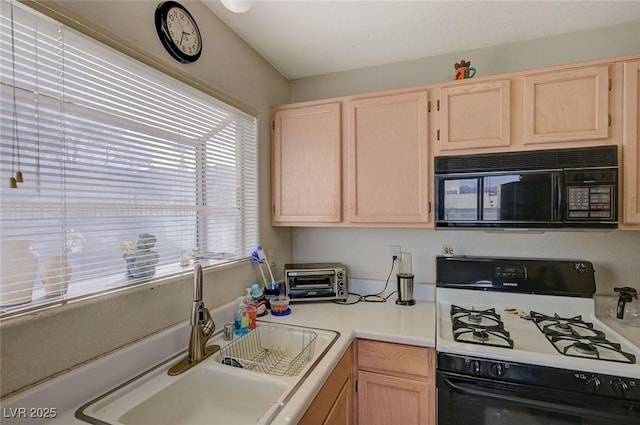 kitchen with gas range oven, sink, and light brown cabinets