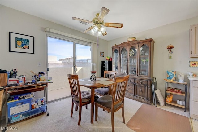 carpeted dining space with a water view and ceiling fan